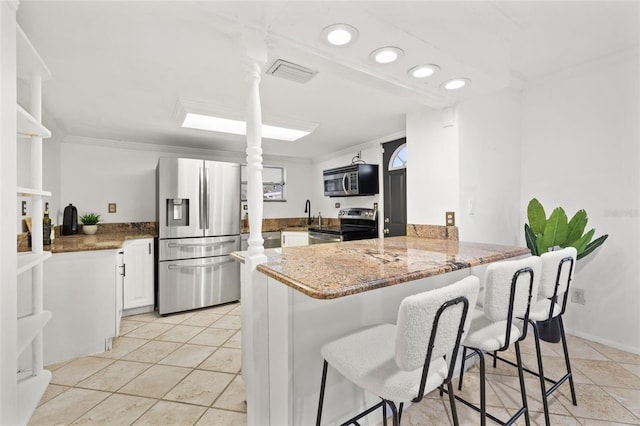 kitchen with visible vents, ornamental molding, a peninsula, stainless steel appliances, and stone counters