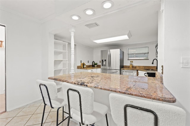 kitchen with light stone counters, visible vents, appliances with stainless steel finishes, a sink, and a peninsula