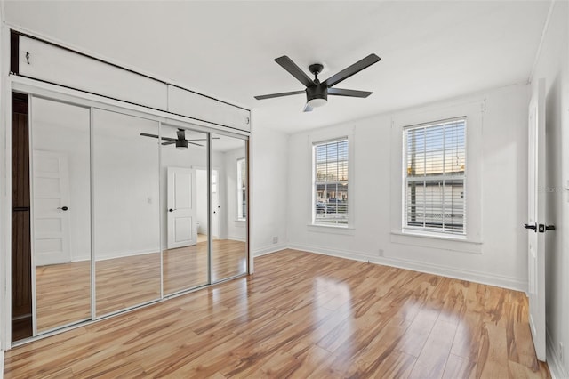 unfurnished bedroom with ceiling fan, a closet, light wood-style flooring, and baseboards