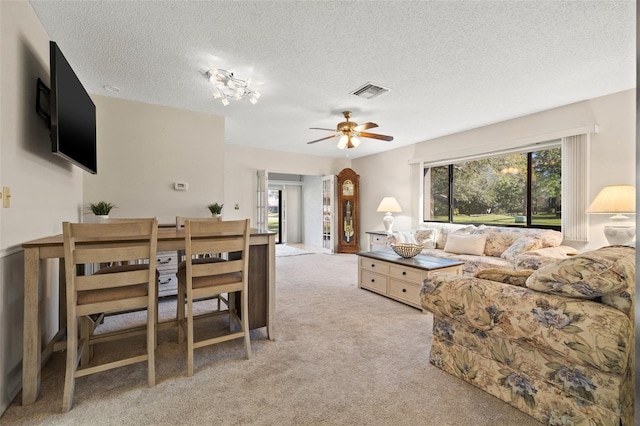 living room with visible vents, light colored carpet, ceiling fan, and a textured ceiling