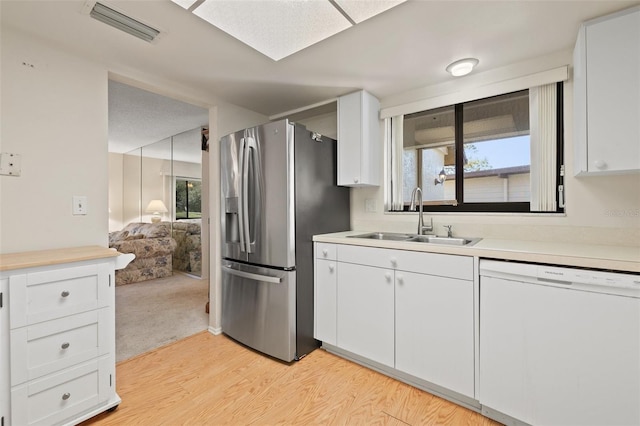 kitchen with stainless steel refrigerator with ice dispenser, visible vents, white cabinets, white dishwasher, and a sink