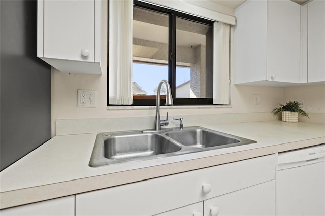 kitchen with light countertops, white dishwasher, a sink, and white cabinetry