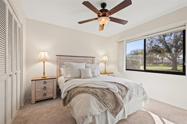 bedroom featuring light carpet, a closet, a ceiling fan, and baseboards