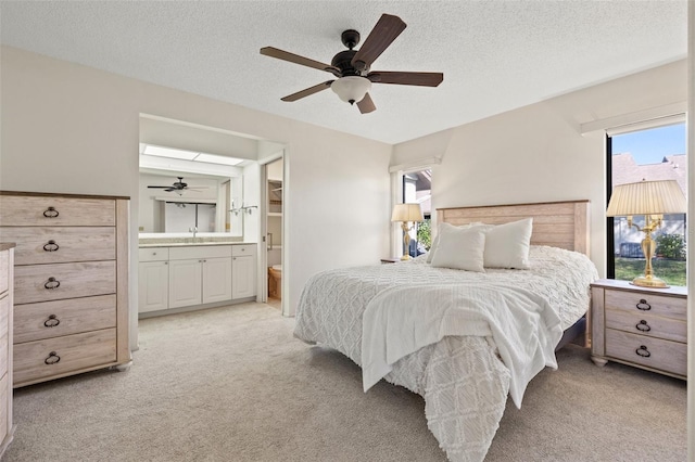 bedroom featuring light carpet, a textured ceiling, a sink, and ensuite bathroom