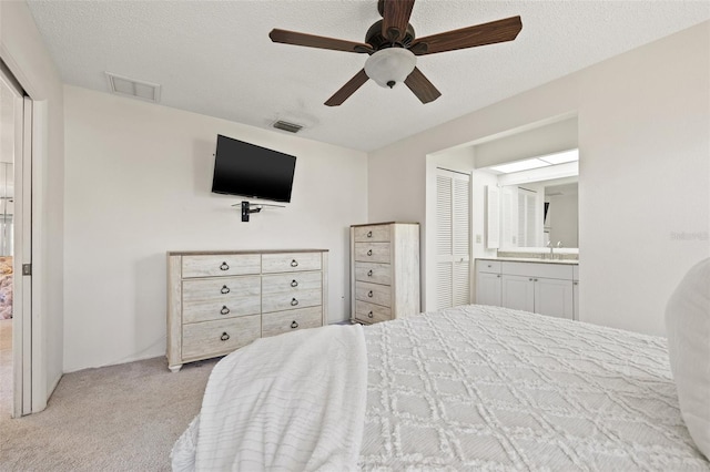 carpeted bedroom with a textured ceiling, a closet, a sink, and visible vents