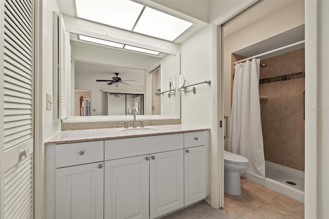 full bath featuring vanity, a skylight, a tile shower, and toilet