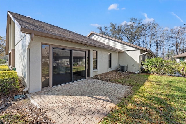 rear view of house featuring central AC, a patio, a lawn, and stucco siding