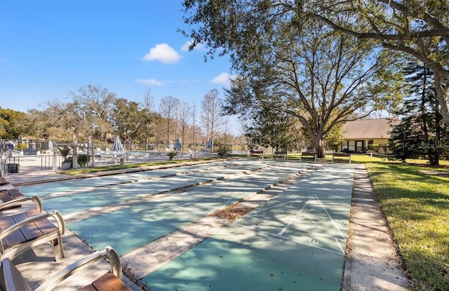 view of community featuring fence, a lawn, and shuffleboard