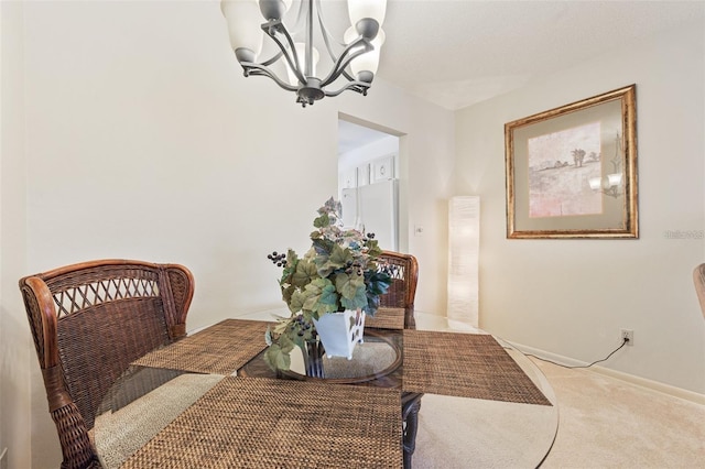 carpeted dining space featuring baseboards and an inviting chandelier