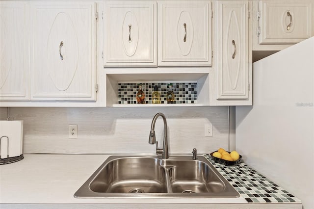 kitchen with light countertops, a sink, and backsplash