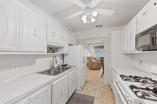 kitchen with white appliances, a sink, visible vents, white cabinets, and light countertops