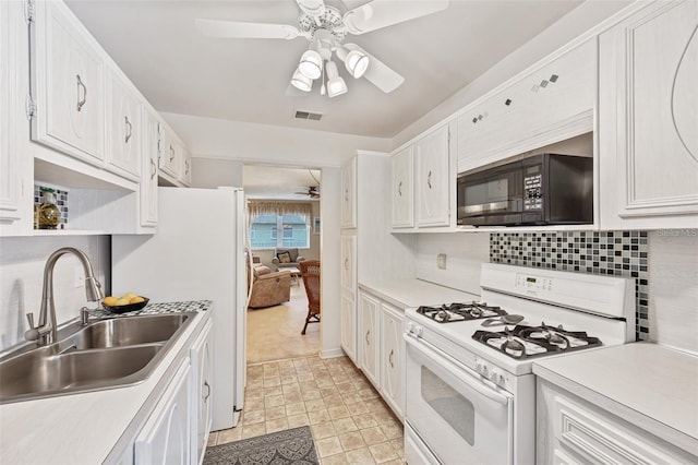 kitchen with visible vents, white gas range, light countertops, black microwave, and a sink