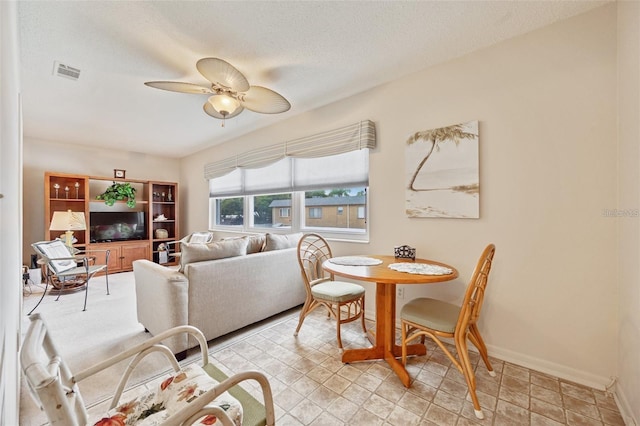 living room featuring a textured ceiling, visible vents, a ceiling fan, and baseboards