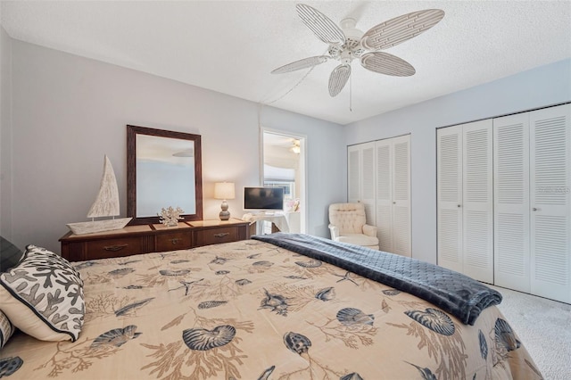 bedroom featuring ceiling fan, carpet floors, a textured ceiling, and two closets