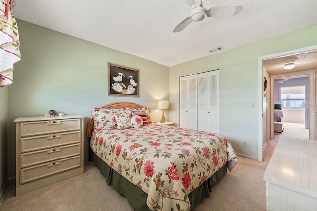 bedroom featuring a textured ceiling, light colored carpet, visible vents, baseboards, and a closet