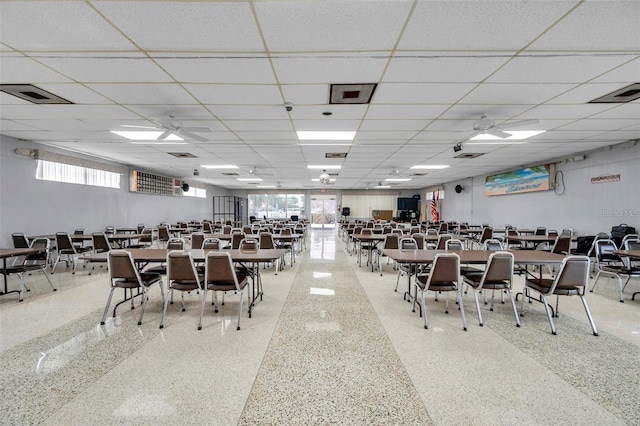 dining area featuring ceiling fan, speckled floor, a drop ceiling, and visible vents