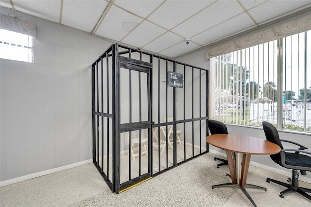 office space featuring speckled floor, a paneled ceiling, and baseboards