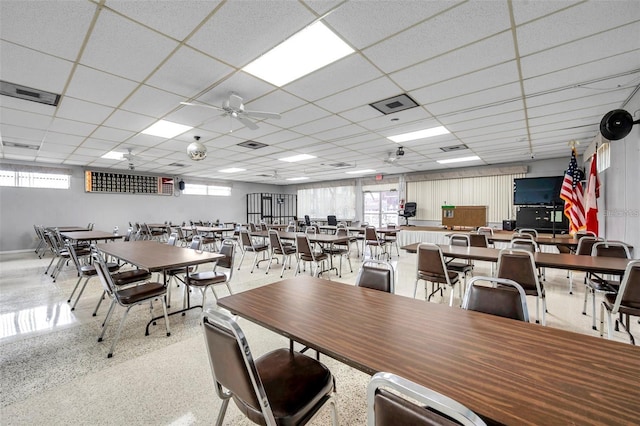 dining space featuring a wealth of natural light, visible vents, a drop ceiling, and speckled floor