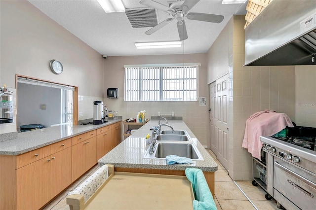 kitchen with range hood, tile walls, light tile patterned flooring, a sink, and light brown cabinets