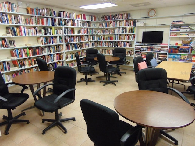 office with tile patterned flooring, a drop ceiling, and wall of books