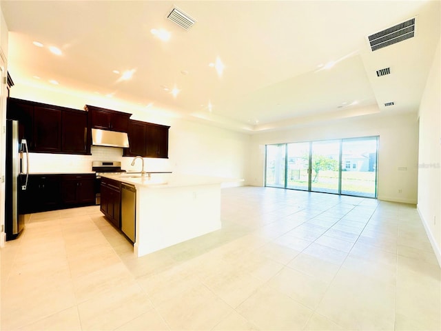 kitchen featuring under cabinet range hood, visible vents, a tray ceiling, and stainless steel appliances