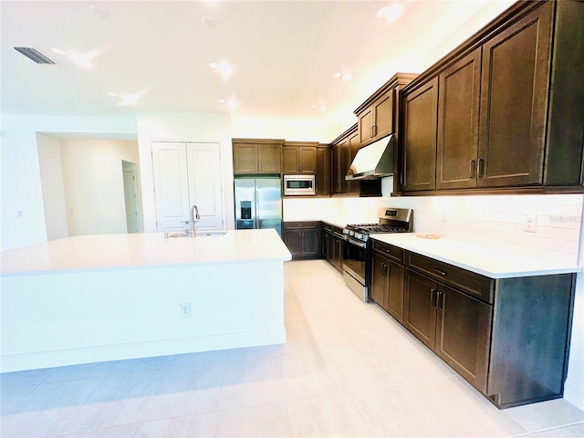 kitchen featuring visible vents, appliances with stainless steel finishes, a sink, an island with sink, and under cabinet range hood