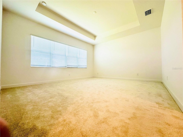 unfurnished room featuring baseboards, visible vents, a tray ceiling, and carpet flooring