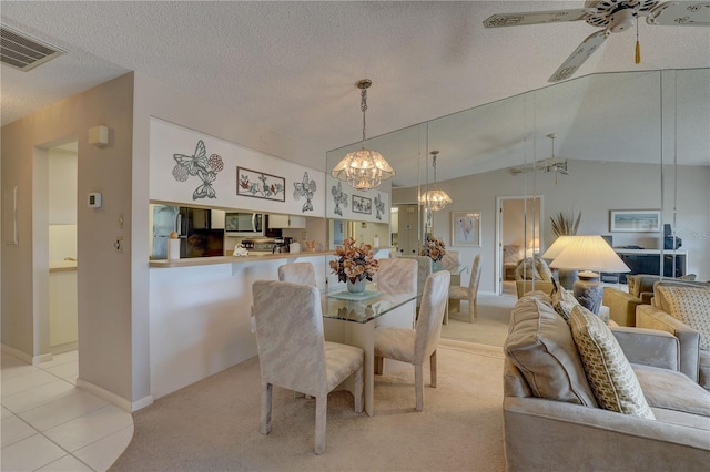 dining space with a textured ceiling, lofted ceiling, light colored carpet, ceiling fan with notable chandelier, and visible vents