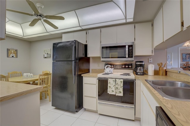 kitchen with electric range, stainless steel microwave, freestanding refrigerator, light countertops, and a sink