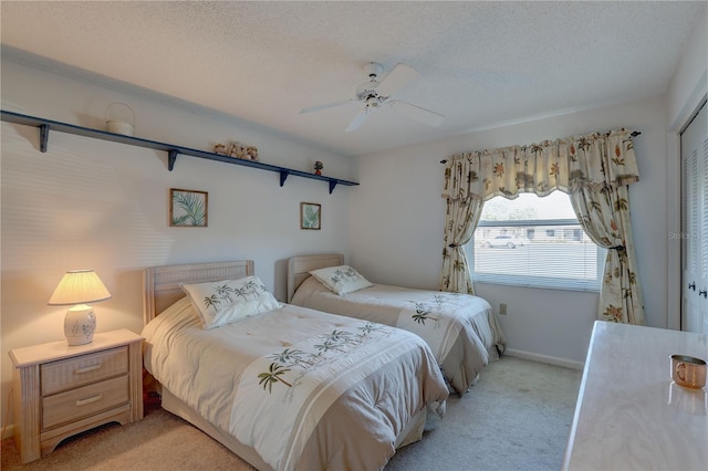 bedroom featuring a closet, light colored carpet, a ceiling fan, a textured ceiling, and baseboards