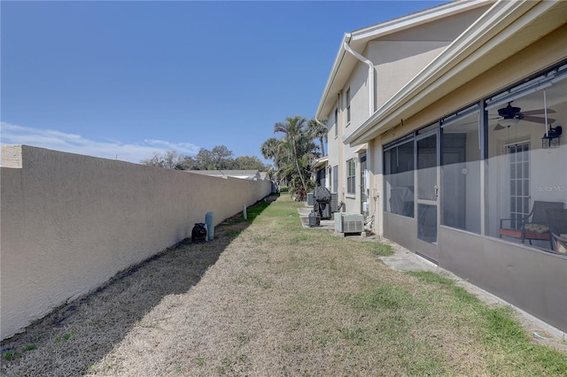 view of yard with a ceiling fan, fence, and central AC