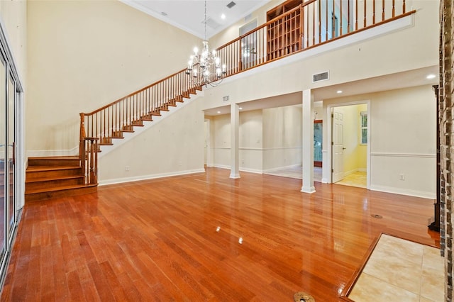 unfurnished living room featuring visible vents, a notable chandelier, stairway, and wood finished floors