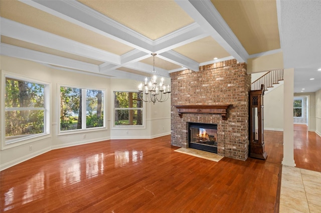 unfurnished living room with plenty of natural light, coffered ceiling, a fireplace, and wood finished floors