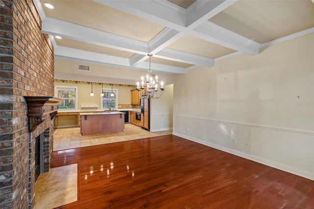 interior space with light wood-type flooring, a fireplace, visible vents, and beamed ceiling