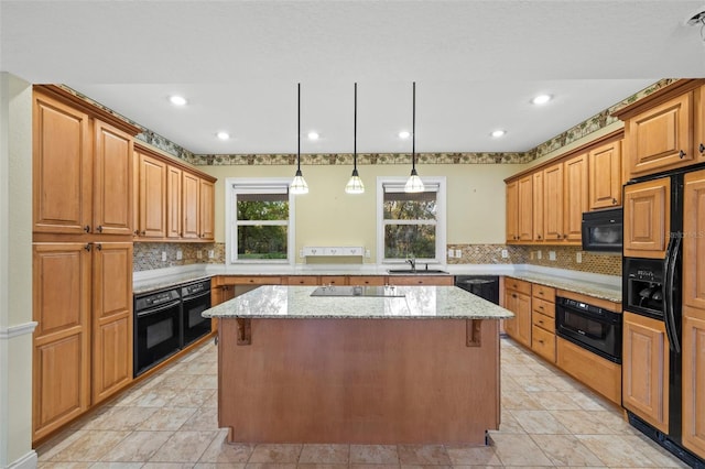 kitchen featuring light stone counters, a kitchen island, a sink, backsplash, and black appliances