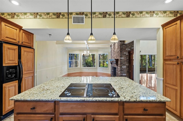 kitchen featuring light stone counters, visible vents, a kitchen island, and black electric stovetop