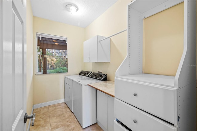 laundry area with cabinet space, light tile patterned floors, baseboards, and independent washer and dryer