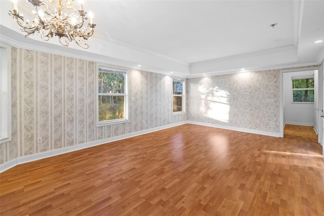 empty room with wallpapered walls, baseboards, crown molding, and wood finished floors