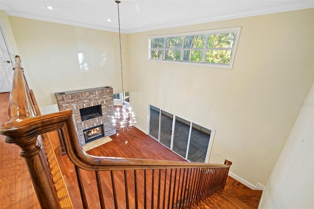 stairs with recessed lighting, ornamental molding, a brick fireplace, wood finished floors, and baseboards