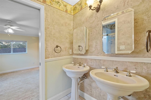 bathroom featuring a ceiling fan, a sink, baseboards, and wallpapered walls