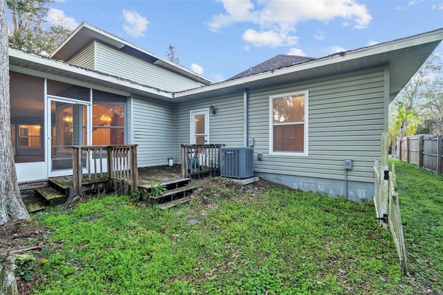 back of property with a sunroom, fence, central AC, and a yard