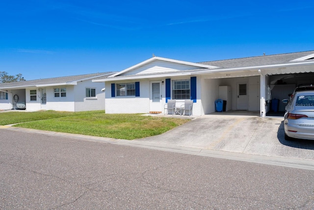 ranch-style house featuring an attached carport, brick siding, driveway, and a front lawn