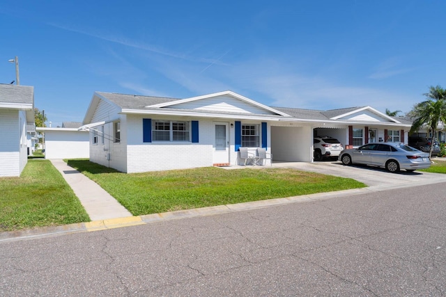 ranch-style house featuring a carport, brick siding, a front yard, and driveway