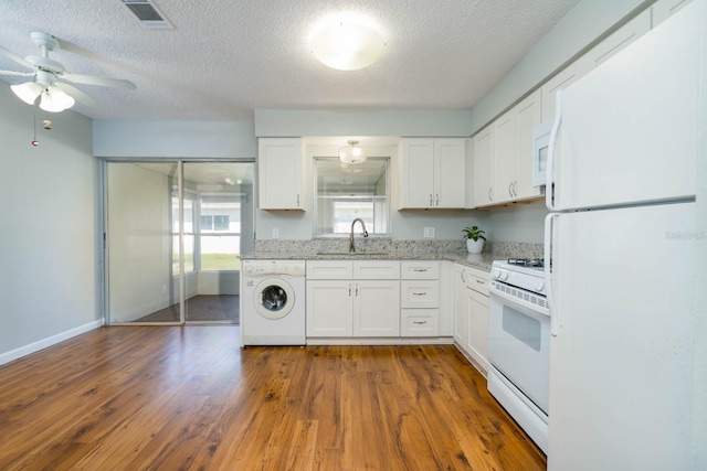 kitchen with white appliances, washer / dryer, visible vents, dark wood-type flooring, and a sink