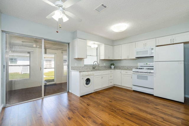 kitchen with dark wood-style flooring, visible vents, a sink, washer / dryer, and white appliances