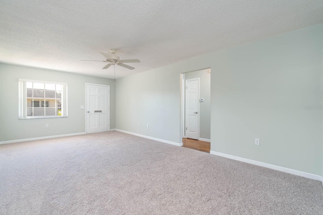 carpeted spare room featuring ceiling fan, baseboards, and a textured ceiling