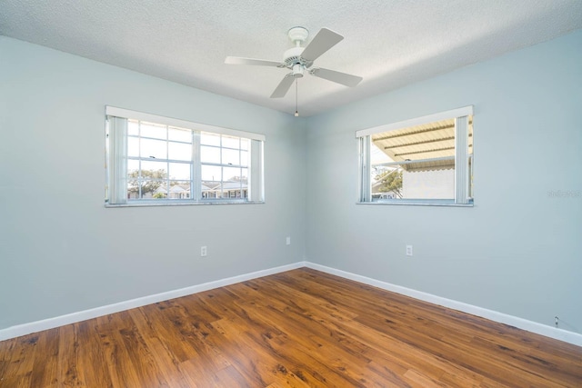 spare room with a textured ceiling, baseboards, and wood finished floors