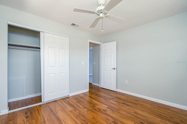 unfurnished bedroom with baseboards, visible vents, wood finished floors, a textured ceiling, and a closet