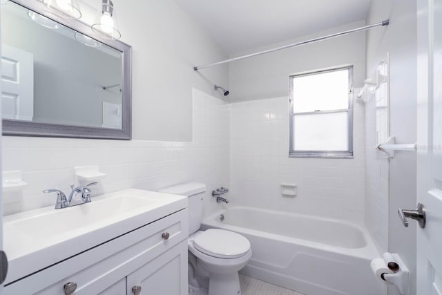 full bath with a wainscoted wall, tile walls, toilet, vanity, and  shower combination