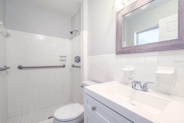 full bathroom with tiled shower, wainscoting, toilet, vanity, and tile walls